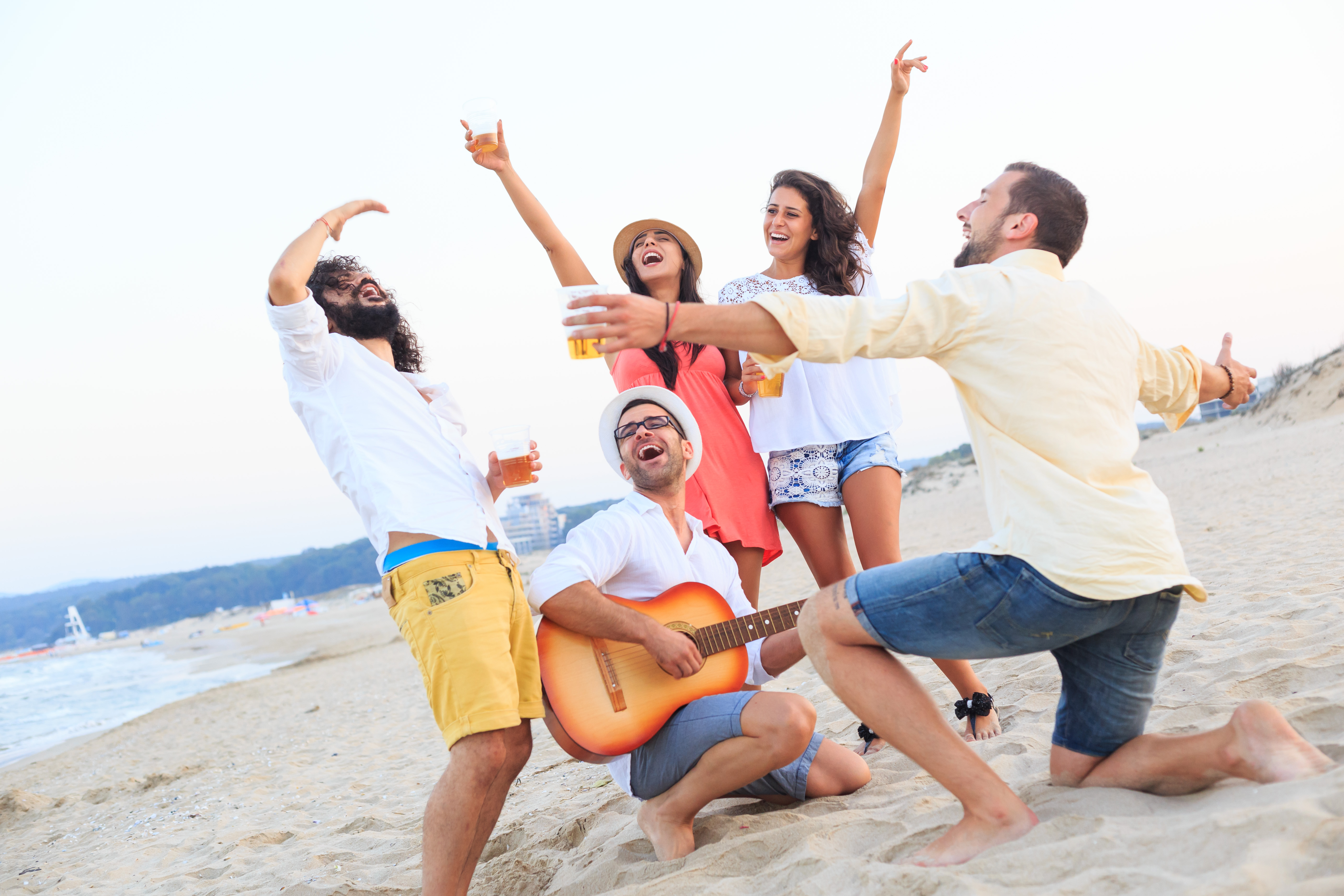 Friends celebrating and drinking beer on beach