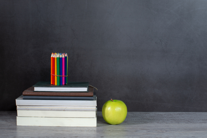 Stack of books and pencil on the table with blackboard background