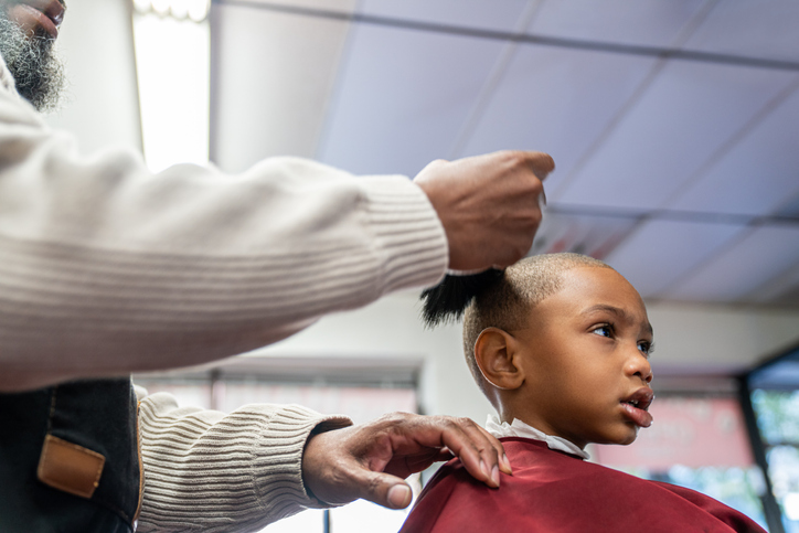 Black customers receive a haircut from barbers at a Black owned Barbershop
