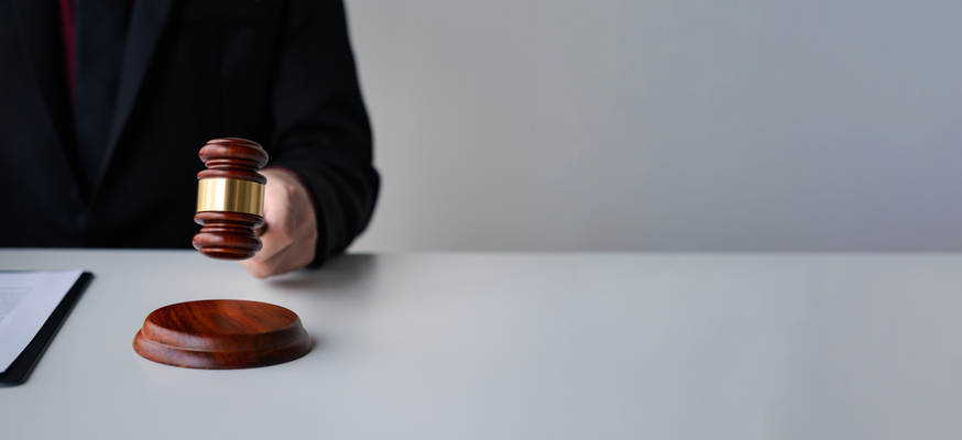 Close up view of male lawyer working and touching Gavel hammer on the table. Legal services concept.