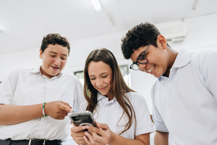 Friends using mobile phone in school classroom
