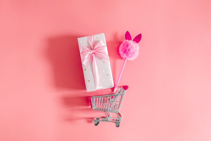 One gift box with a bow and a bunny handle in a mini cart on a pink background.