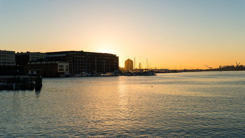 Scenic View of City Buildings and Marina Against a Clear Sunset Sky Over Water
